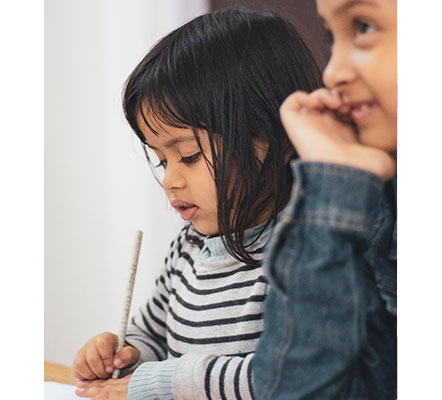 student in striped sweater writing with a pencil