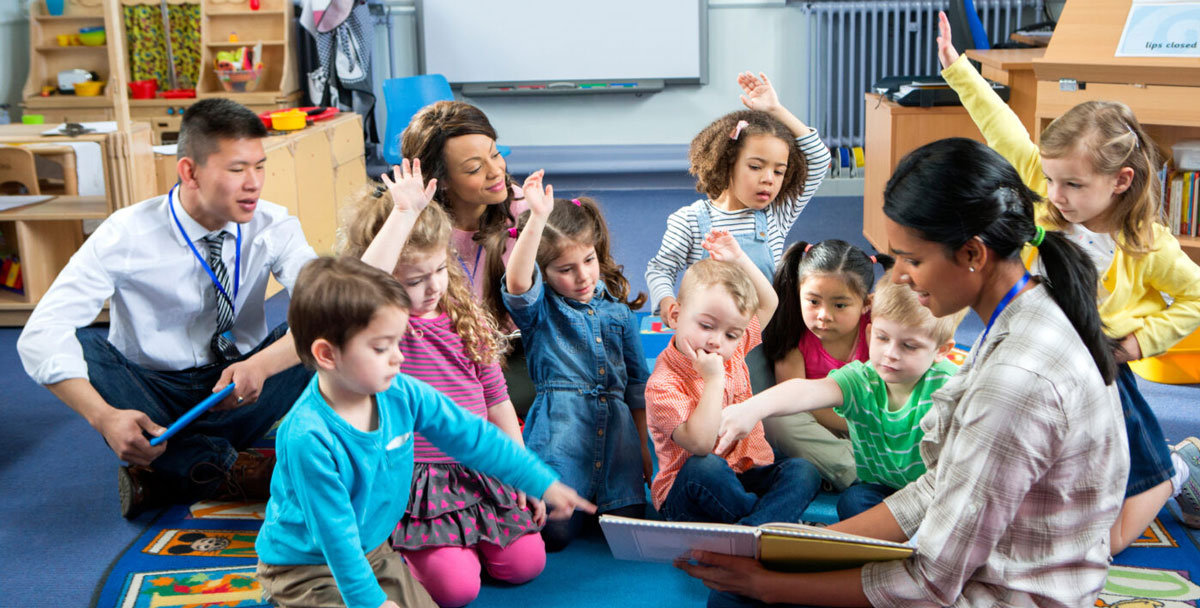 Three teachers sitting on the floor in the classroom